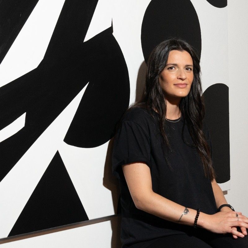 Alice Notarianni, yoga teacher, sitting against a bold black and white painting